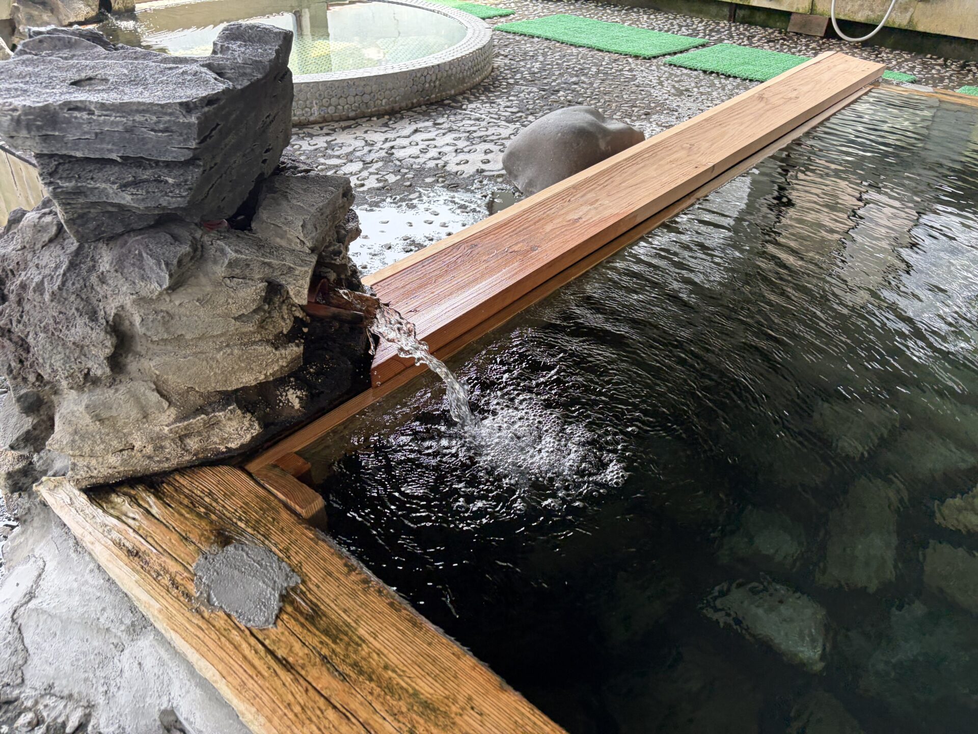 岩組の湯口から湯船に落ちる湯。泡を立てて注がれ続ける