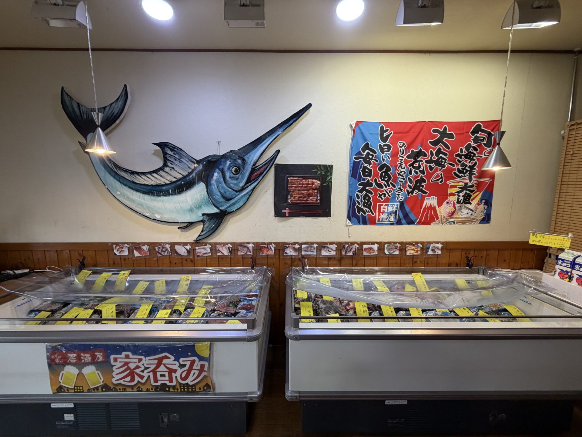 店内全景。カジキの壁飾りと大漁旗、壁一面の魚写真
