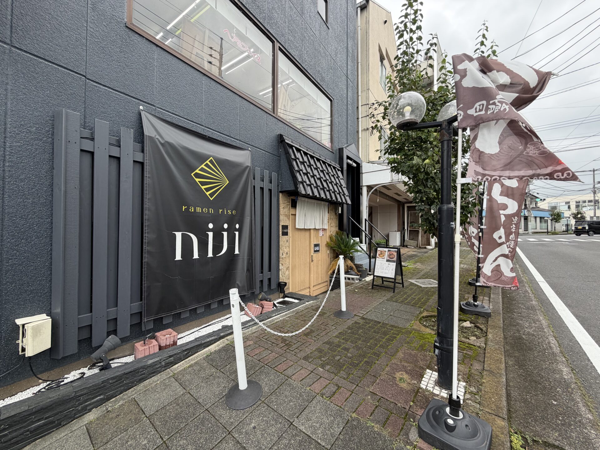 黒い外壁に「ramen rise niji」の垂れ幕がかかる店の外観