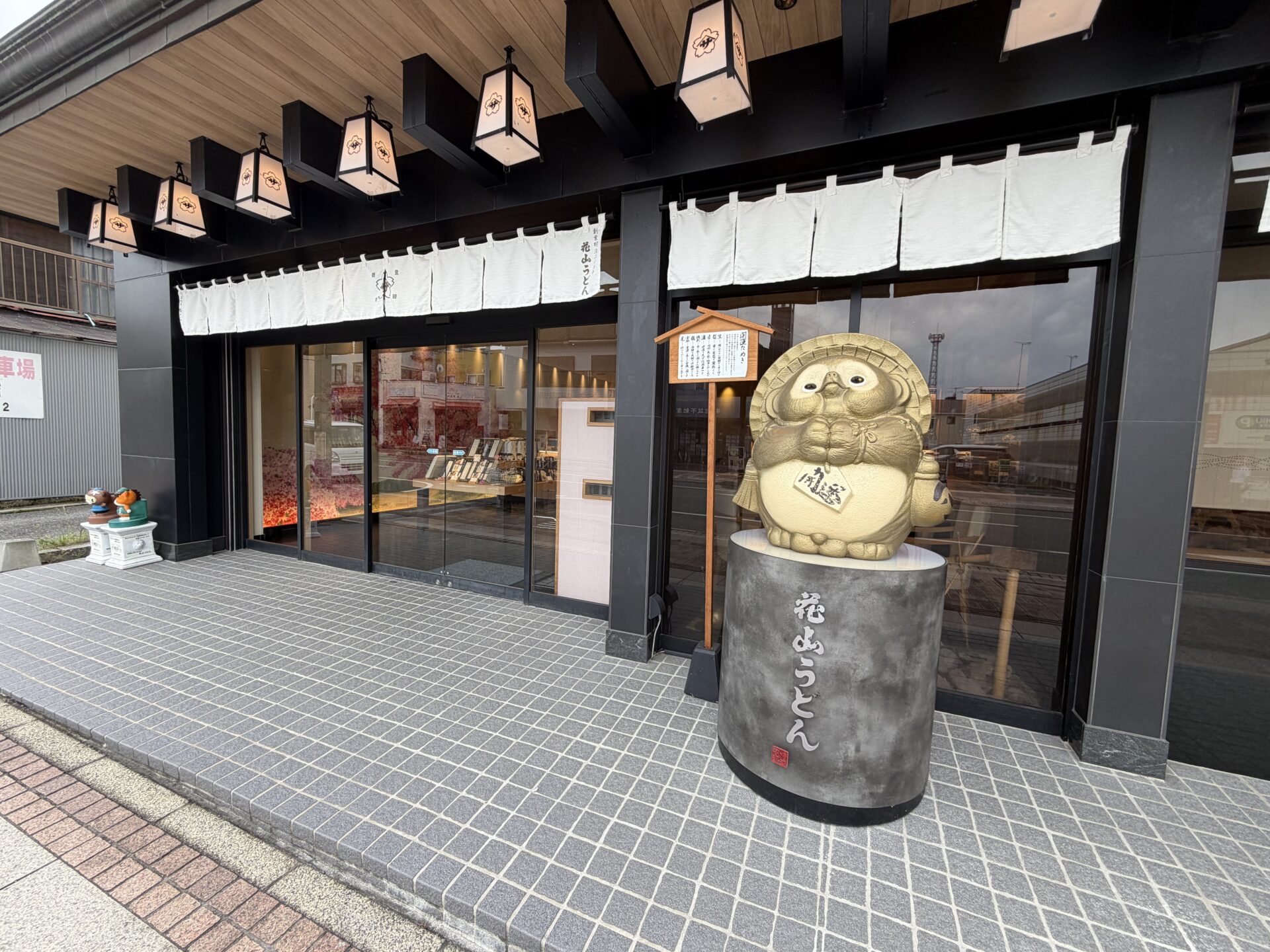 金色のたぬき像が座る花山うどん本店の直売所の入口。お食事処の入口はこの隣