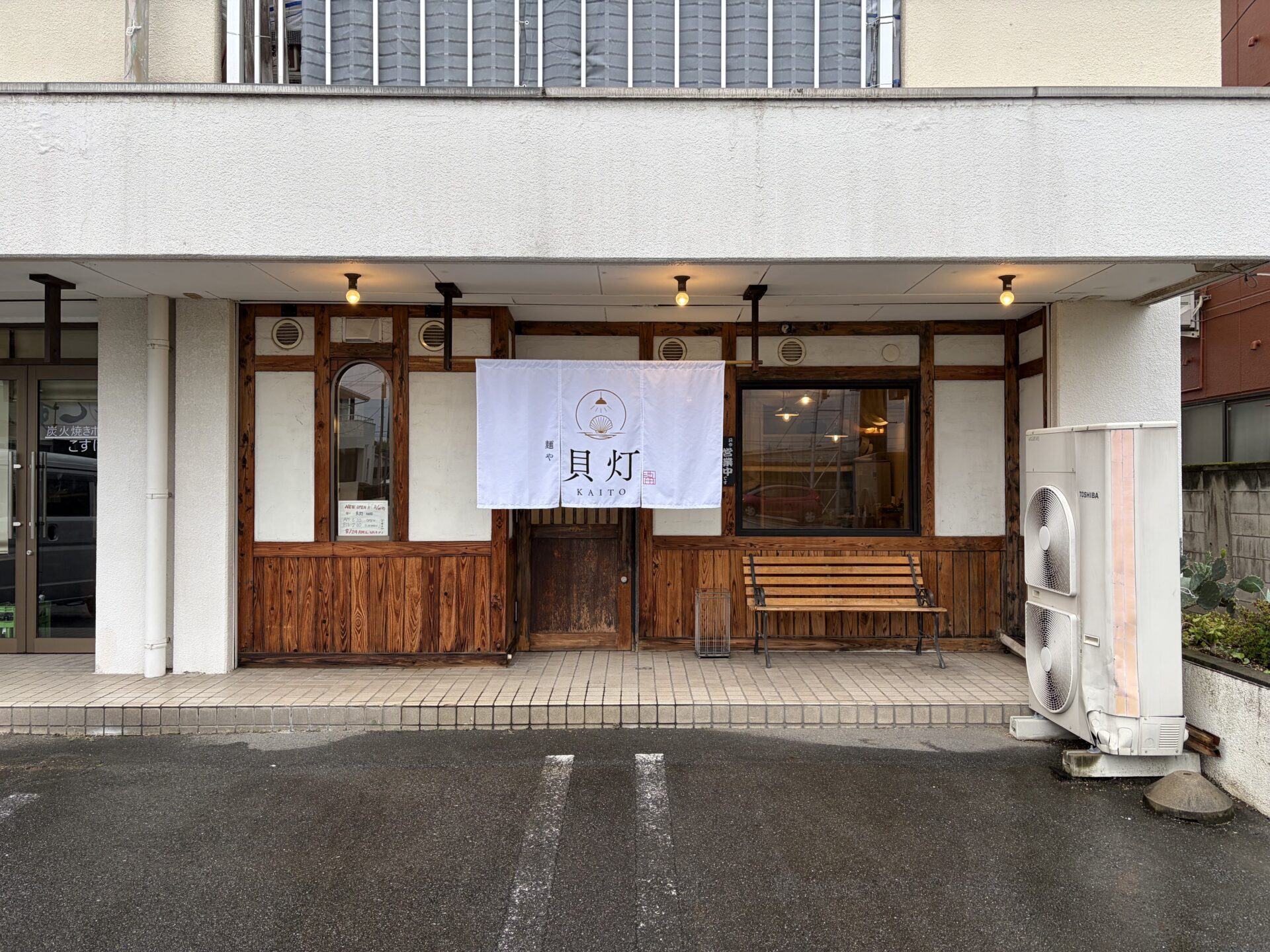 前橋市日吉町「麺や貝灯 KAITO」の外観。木の格子と白い暖簾、店先のベンチ
