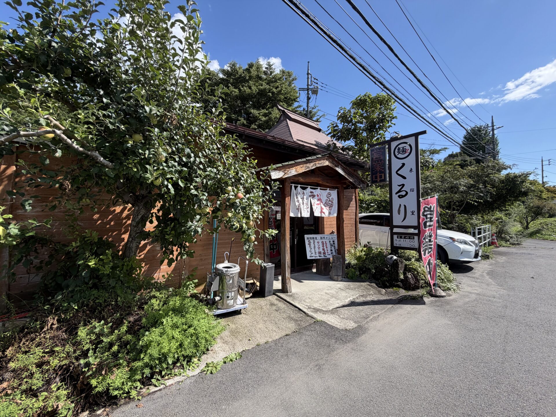 県道側から見た外観。実をつけた木と看板、店先の駐車スペース