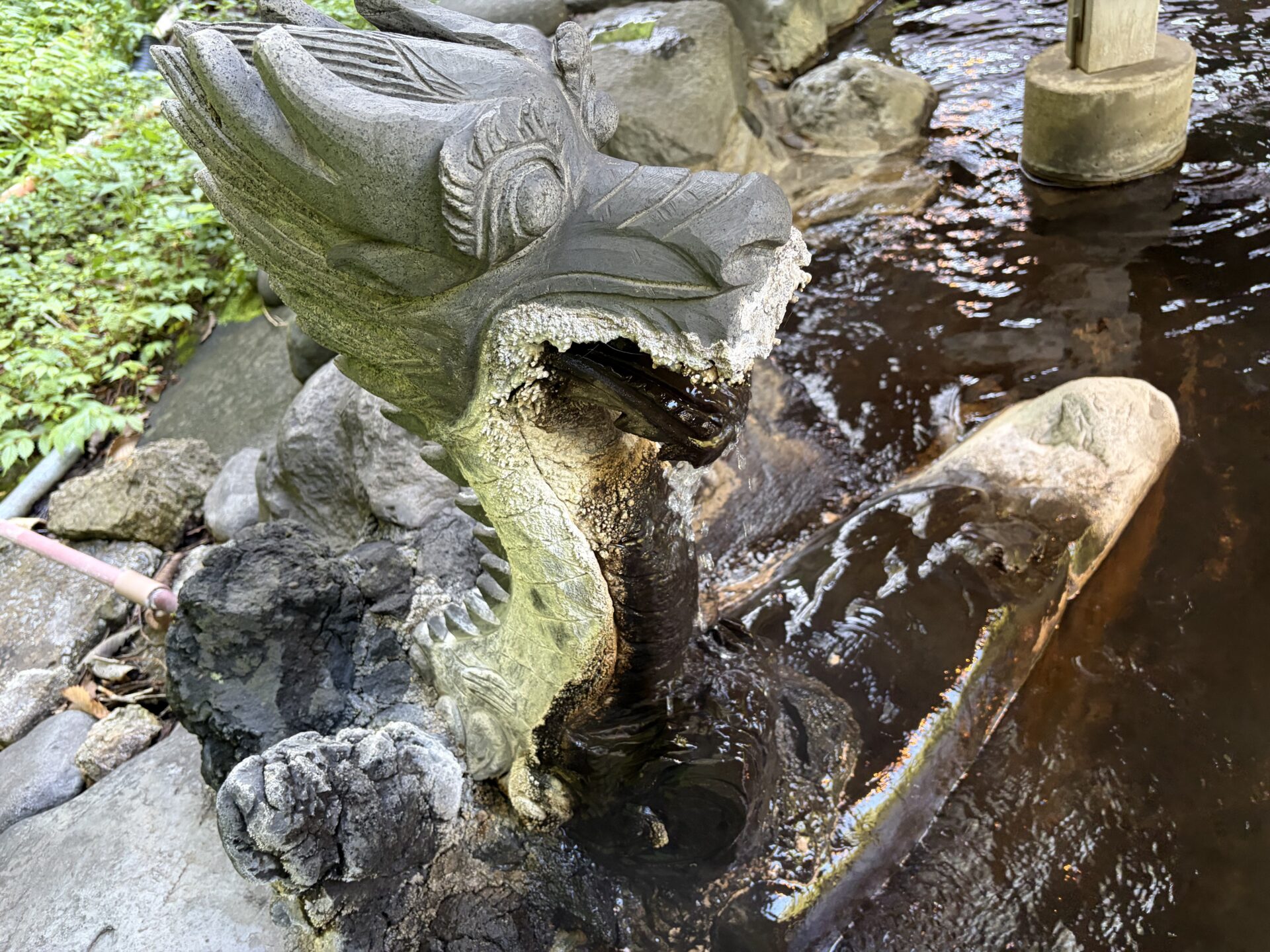 大龍(大露天風呂)の龍の湯口。口元には白い析出がびっしり付き、源泉が絶えず落ちる