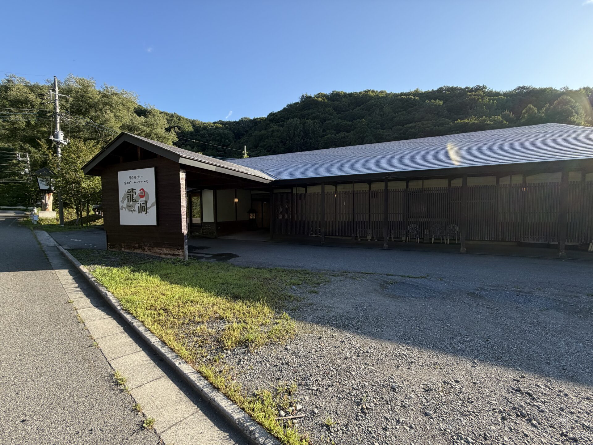 県道63号沿いの外観。「源泉掛流しの湯めぐりテーマパーク」の看板と屋内駐車場