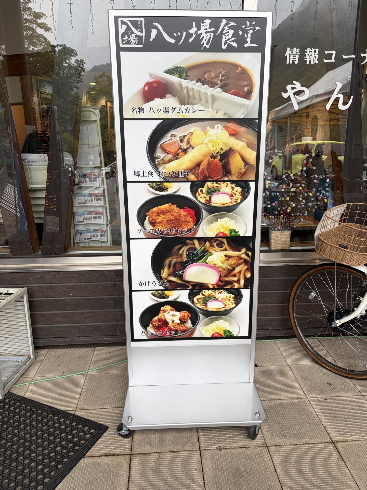 店頭のメニュースタンド。ダムカレー、おつみ団子、ソースカツ丼セットなど