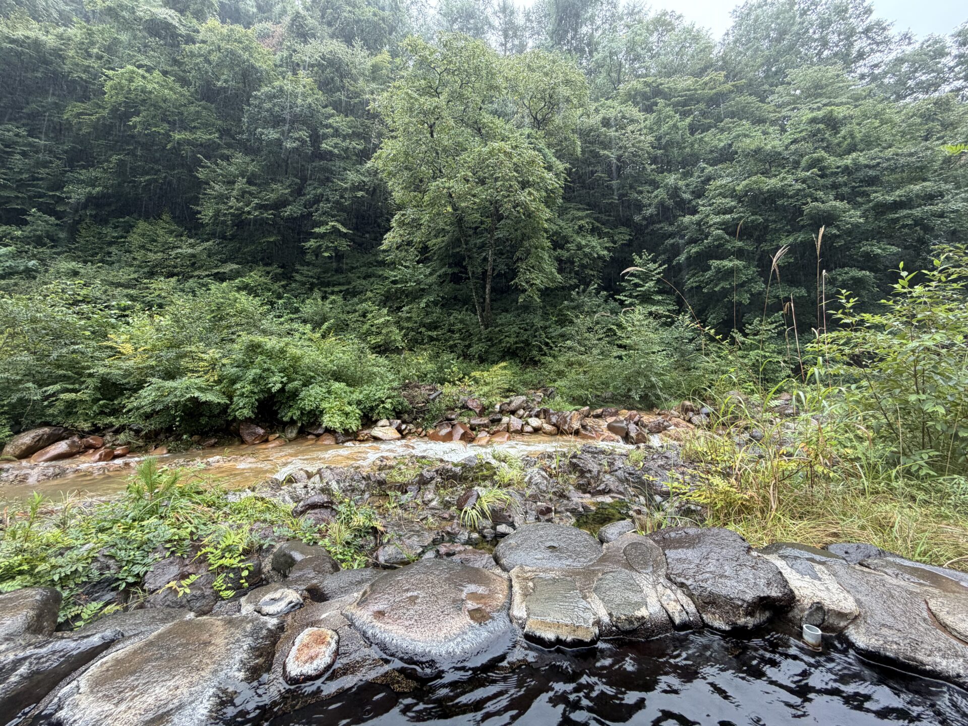 野天風呂から見た川。増水した流れが赤茶の岩の上を走る
