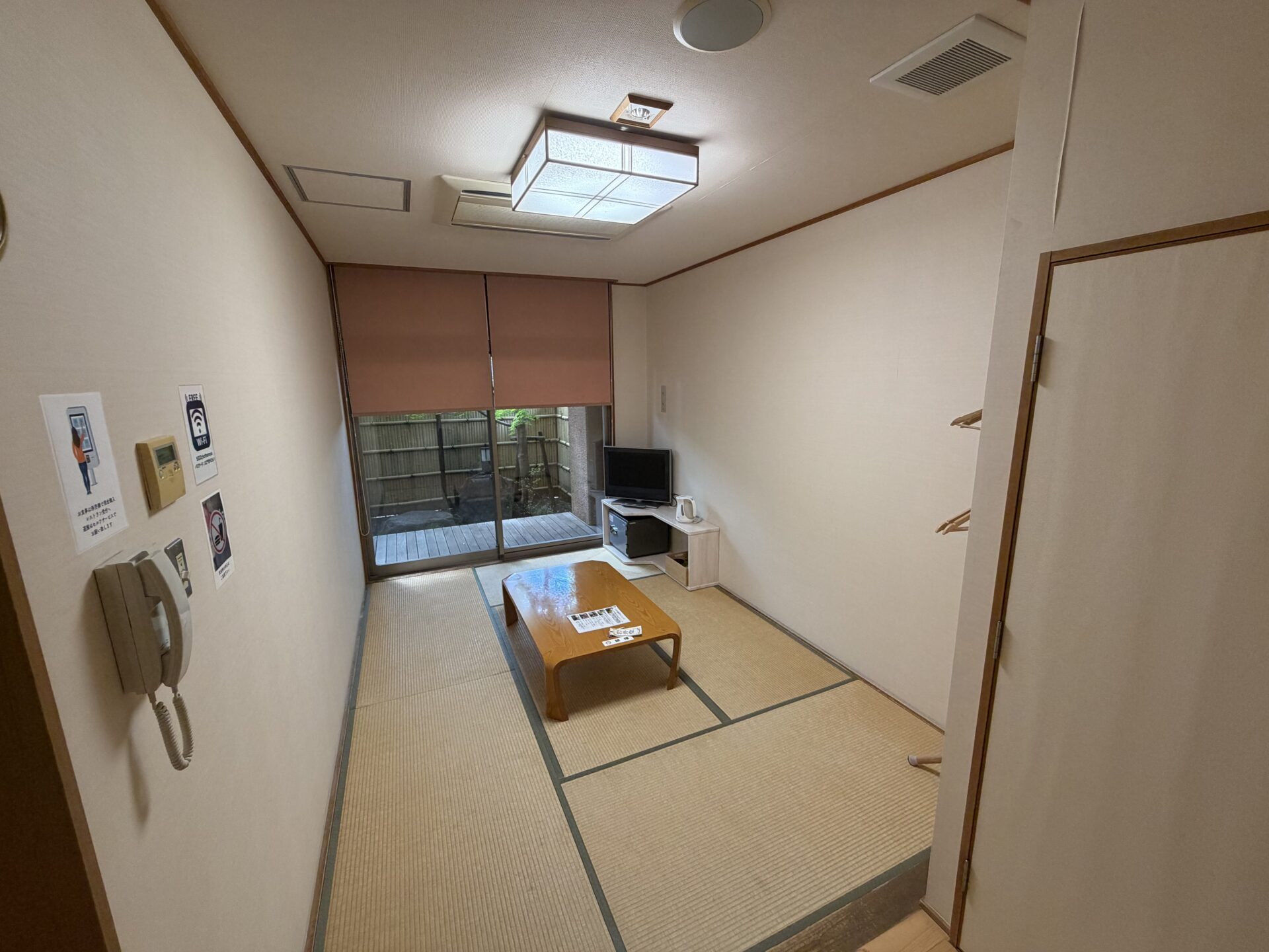 岩井堂の和室。座卓に「岩井堂」の鍵札、奥の窓の外にウッドデッキ
