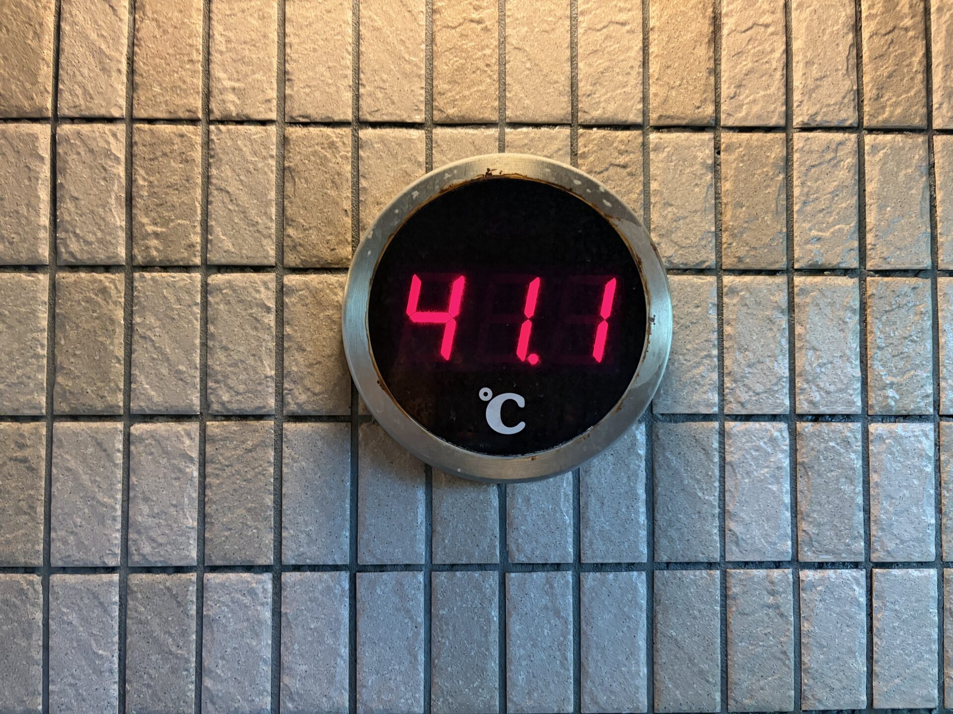 壁の丸型デジタル湯温計。赤いLEDで41.1℃