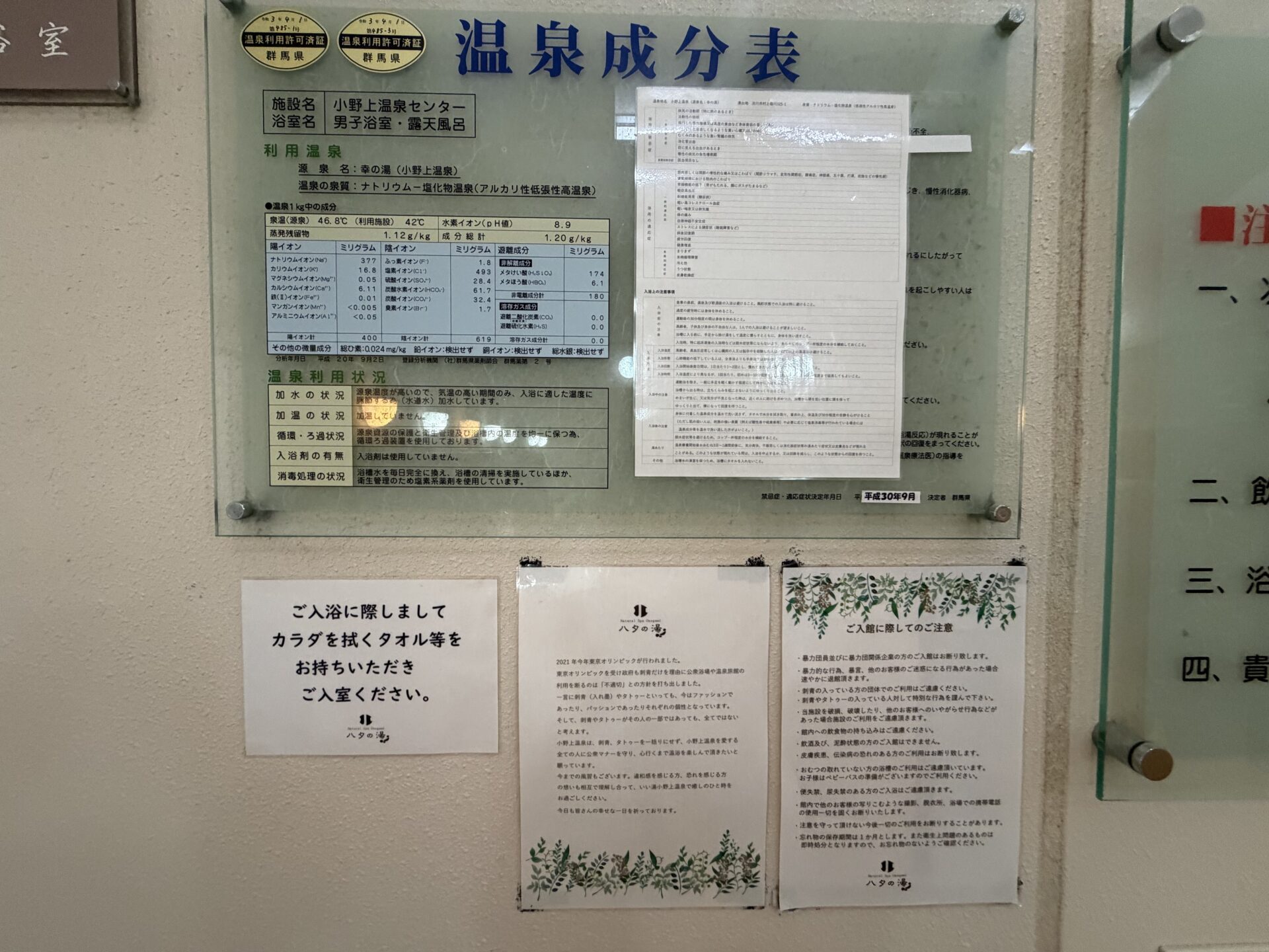 男子浴室入口の掲示群。上に温泉成分表、下にタオル持参のお願い・刺青タトゥーについての文章・ご入館に際してのご注意