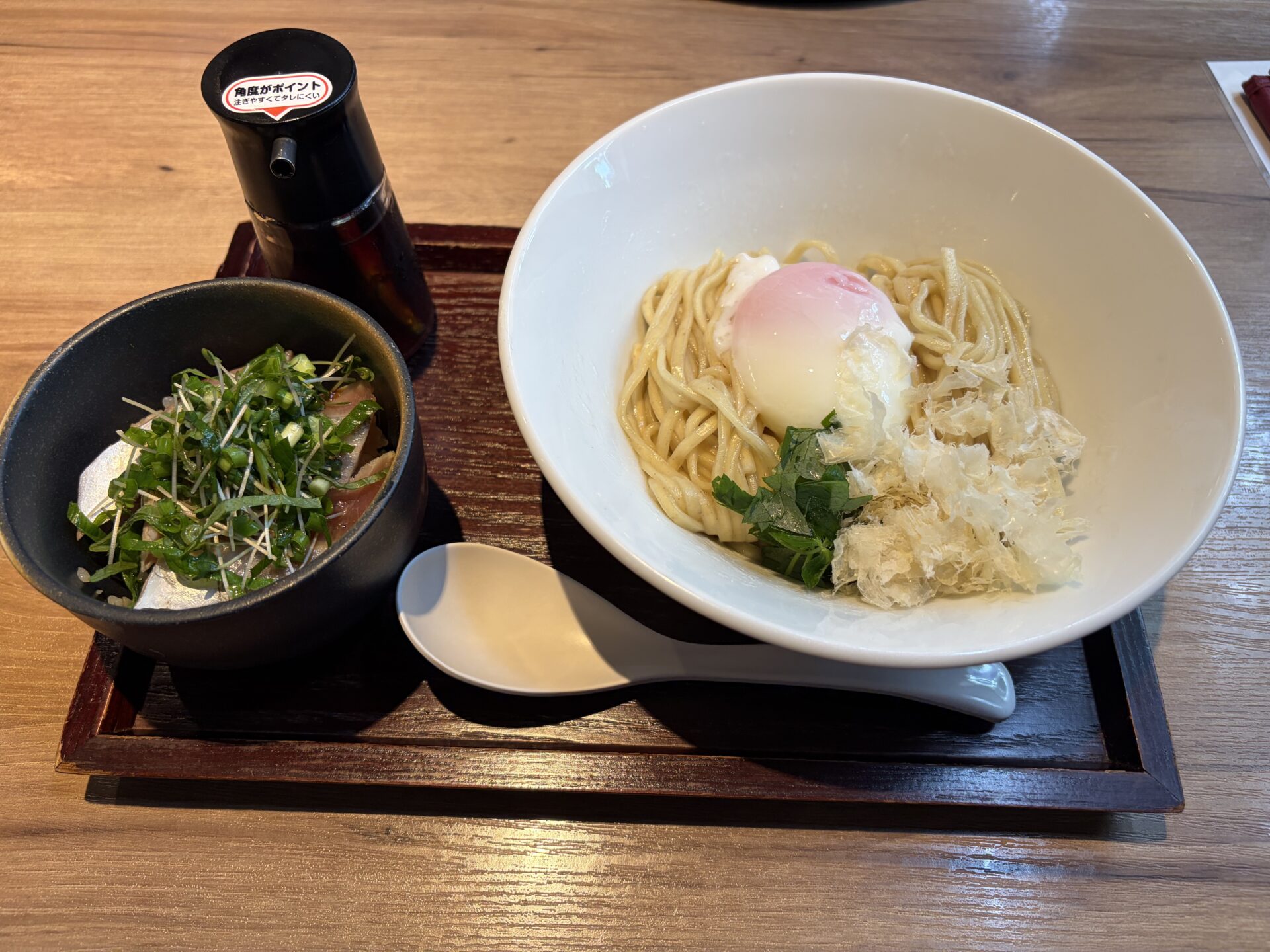 鶏節と温玉のまぜそば（右）と戻り鰹丼（左）。左奥にタレの瓶（店の案内では特製出汁醤油）
