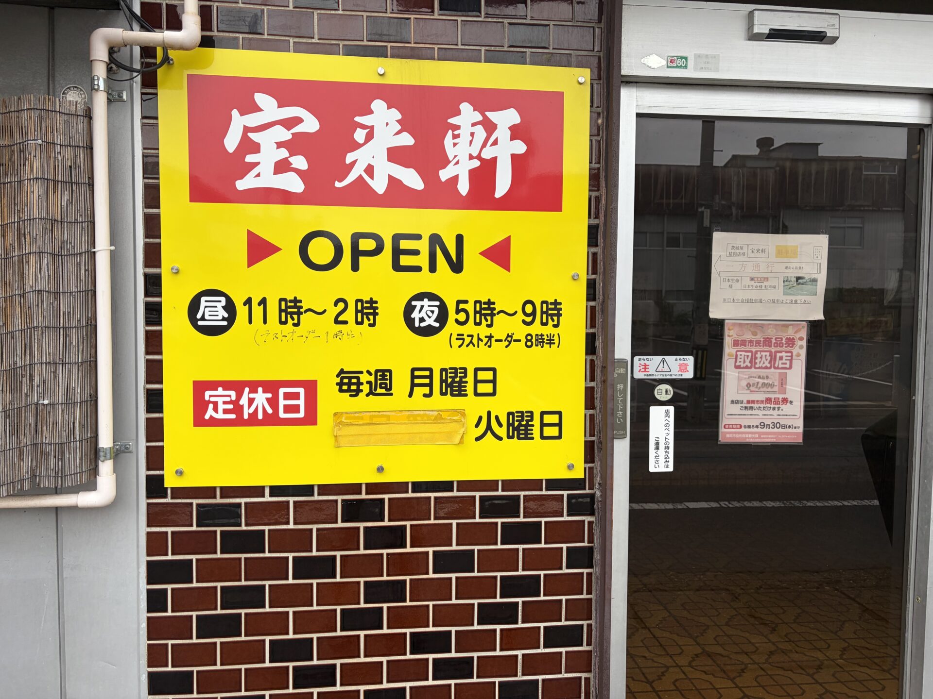 入口の黄色い看板。昼11時〜2時・夜5時〜9時、定休日は毎週月曜日・火曜日