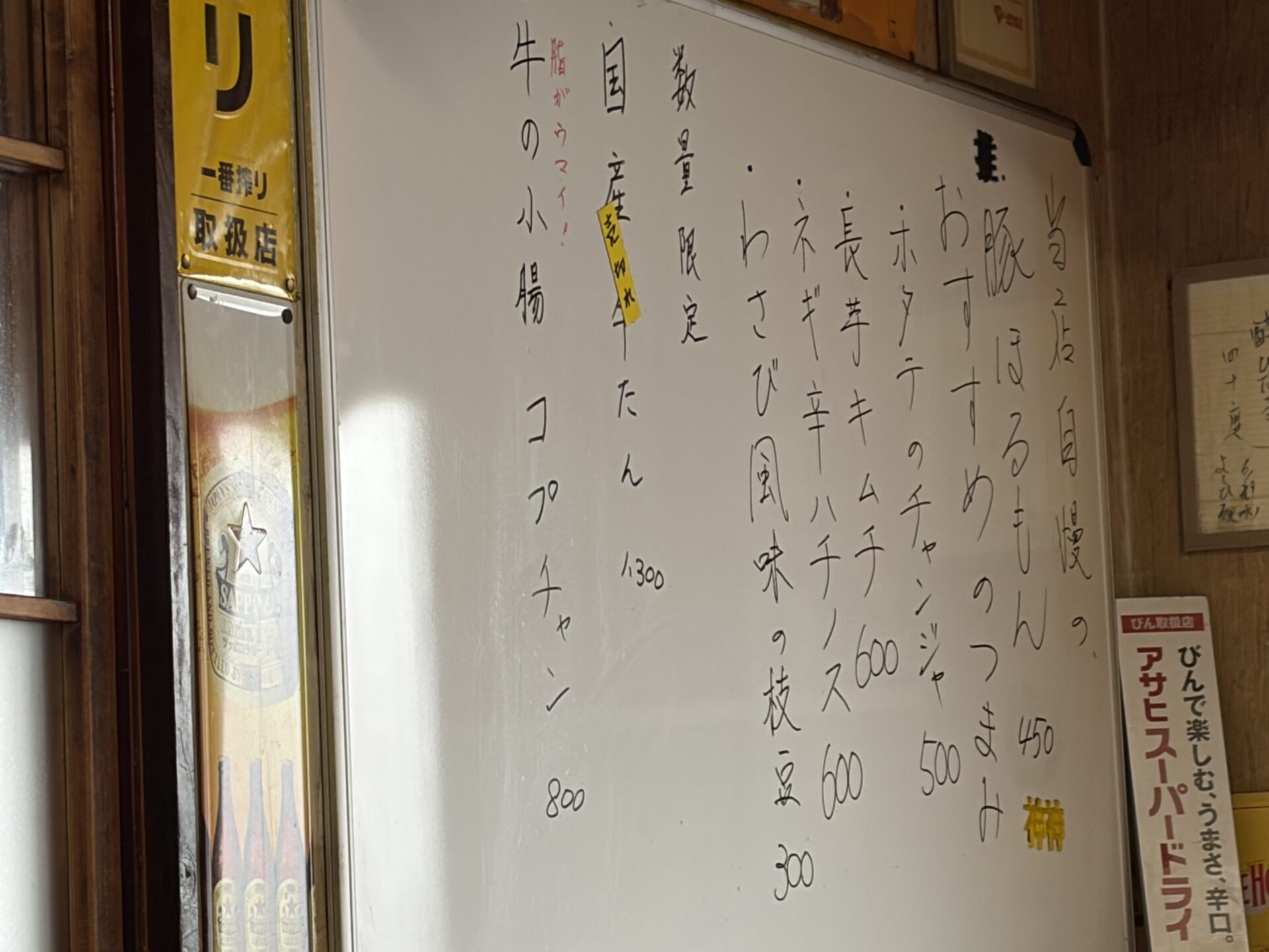 店内のホワイトボード「当店自慢の 豚ほるもん 450」、おすすめのつまみ、数量限定の国産牛たん、コプチャン
