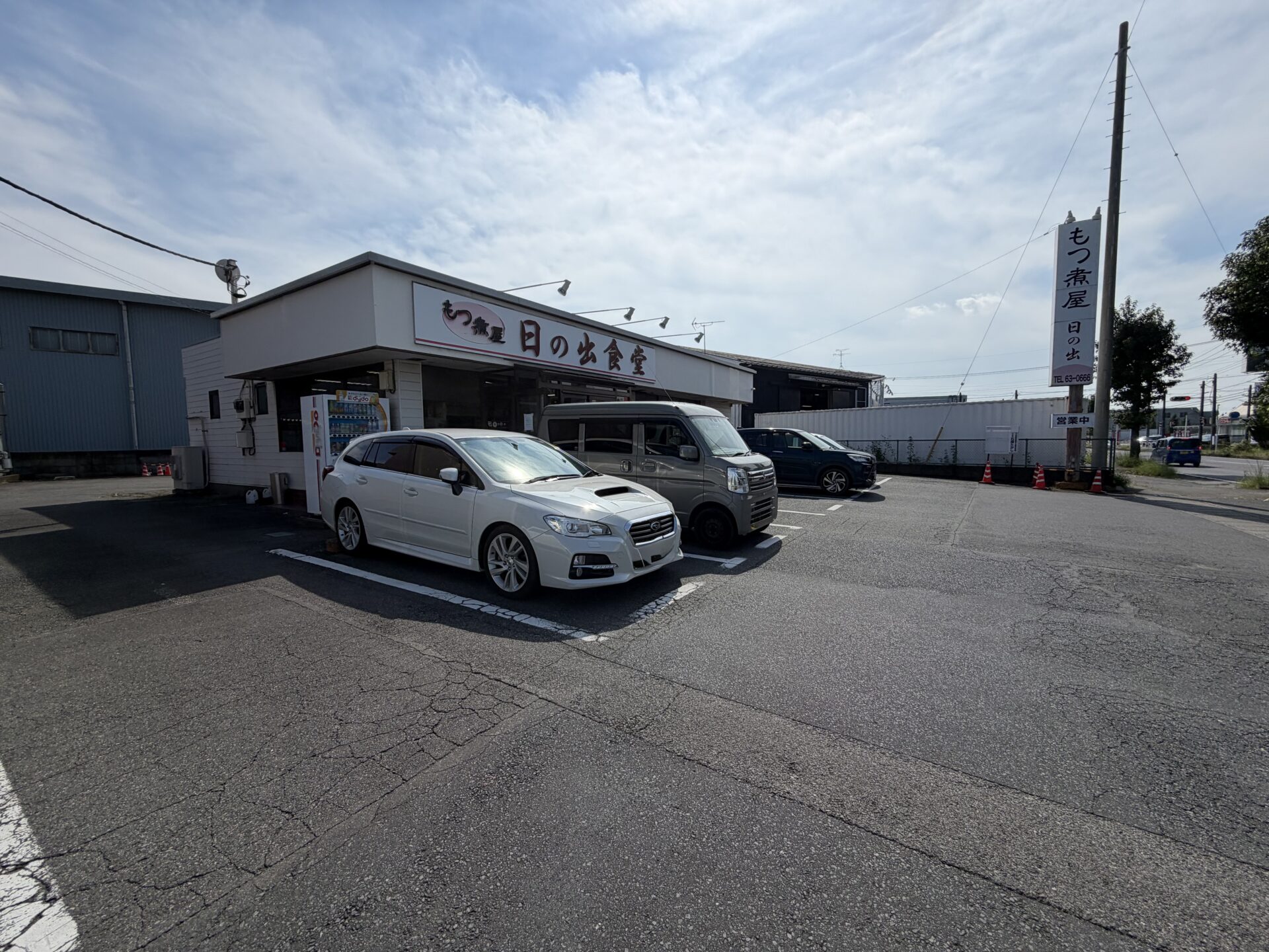 外観。店の看板は「もつ煮屋 日の出食堂」、道路沿いのポール看板には「営業中」の札