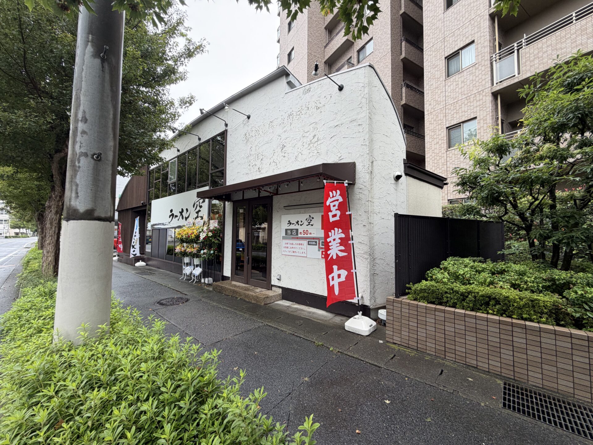 通り側から見た店。白い建物と「営業中」ののぼり