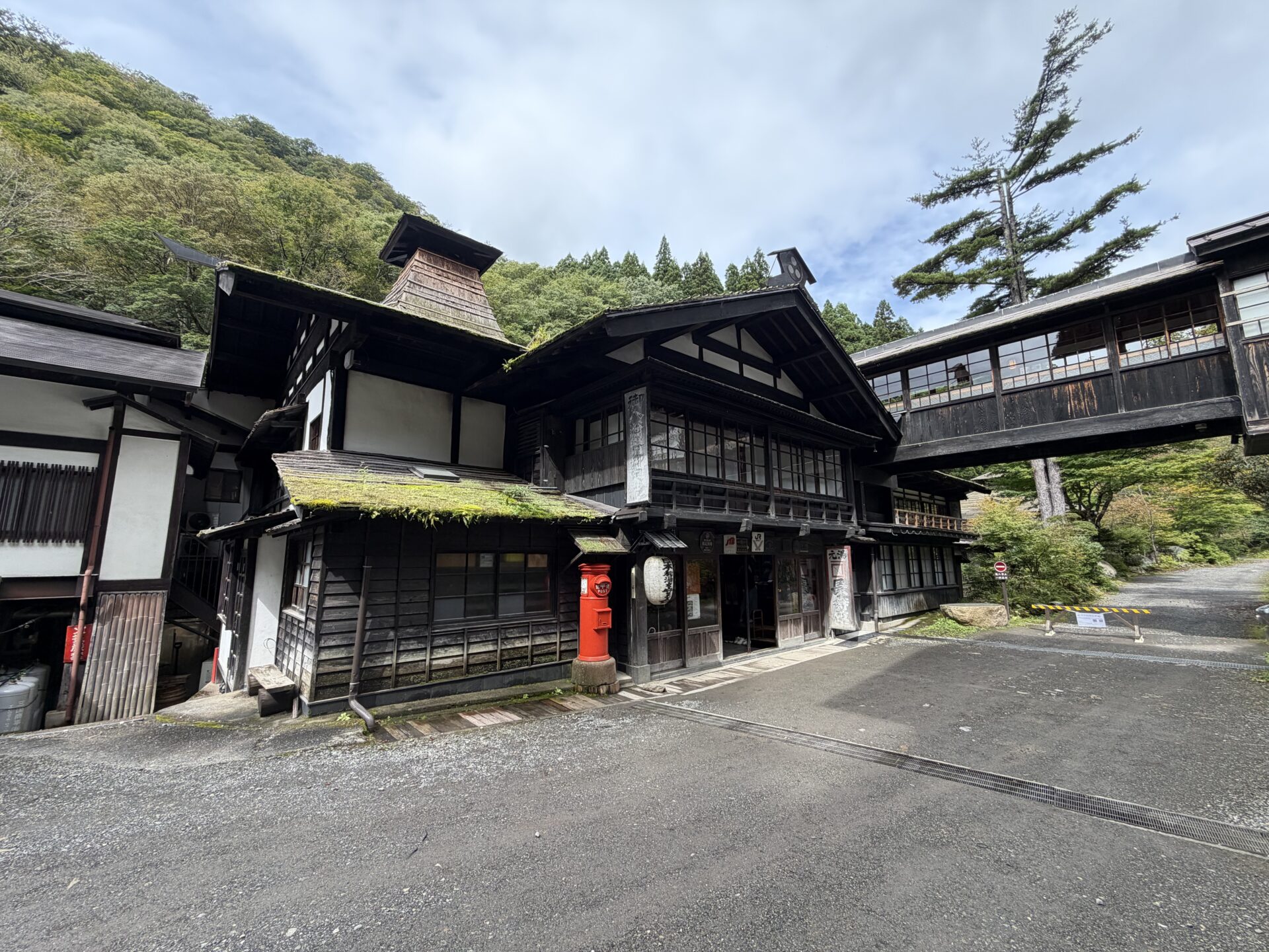 法師温泉 長寿館の外観。木造の本館と渡り廊下、手前の橋