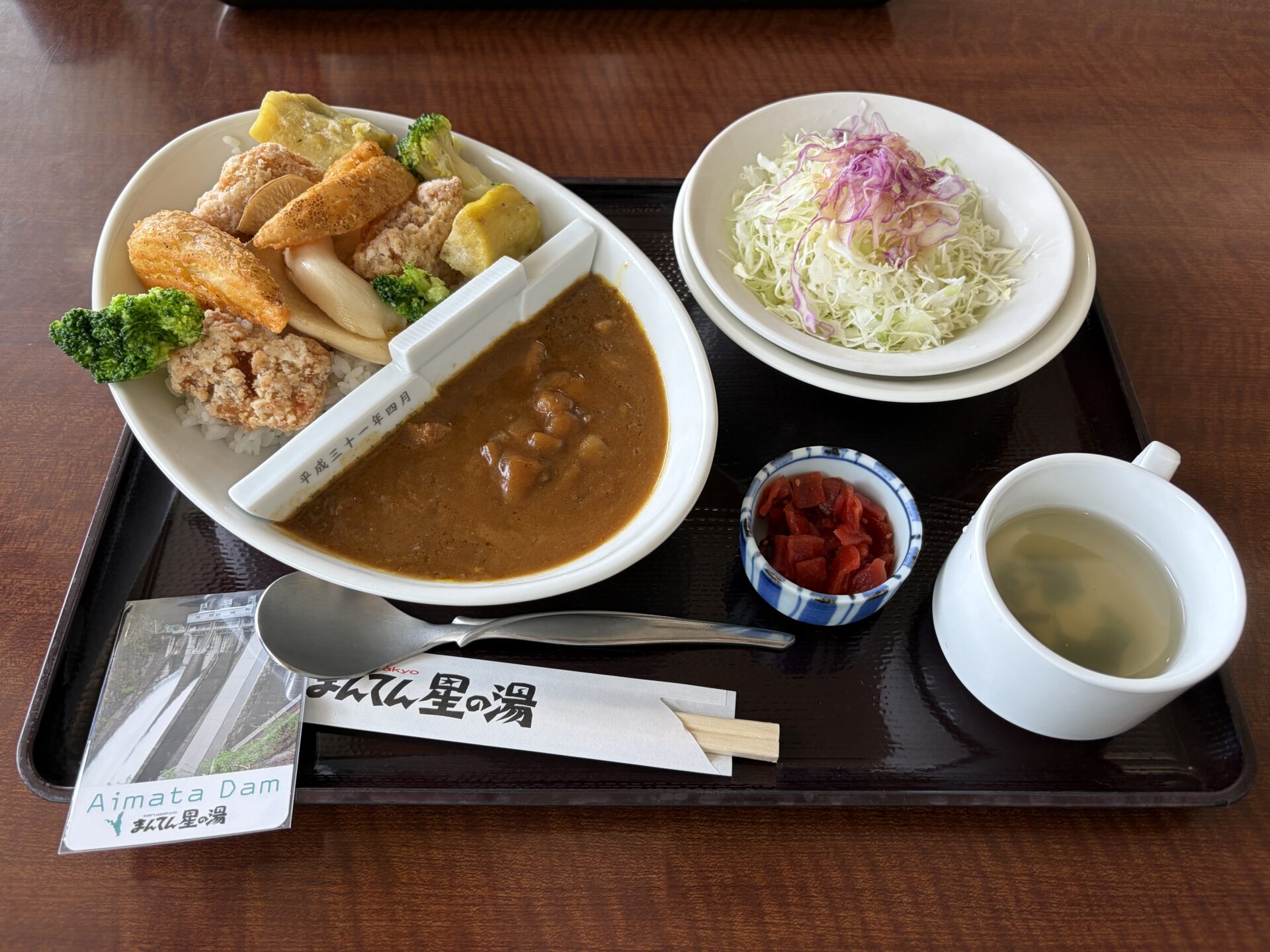 相俣ダムカレー 上州麦豚バージョンの全景。白い仕切り板の堰堤がカレーをせき止め、トレーの端に相俣ダムカードが添えられている