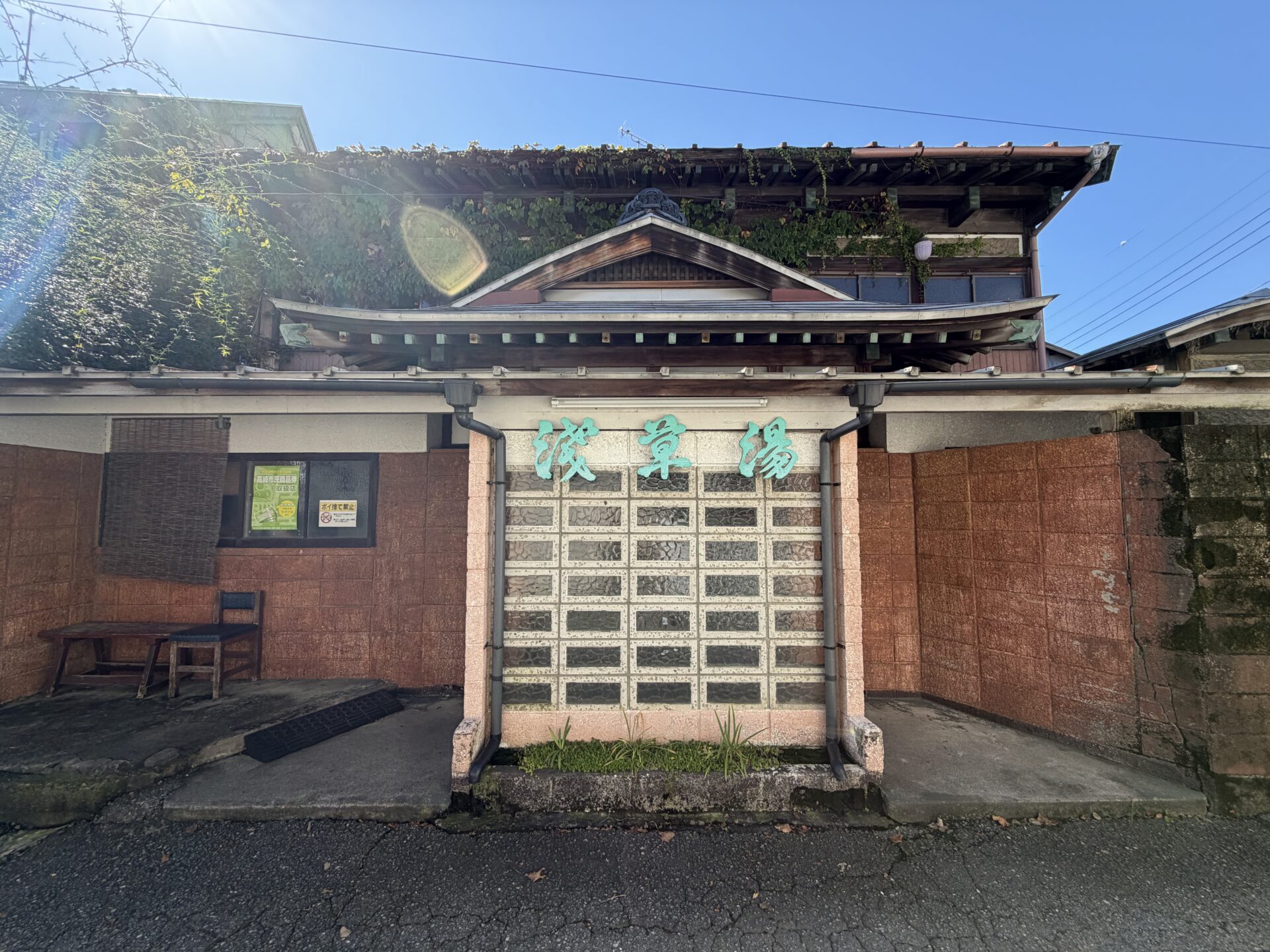浅草湯の正面。社寺風の屋根の下に、ガラスブロックの壁と緑色の「浅草湯」の文字