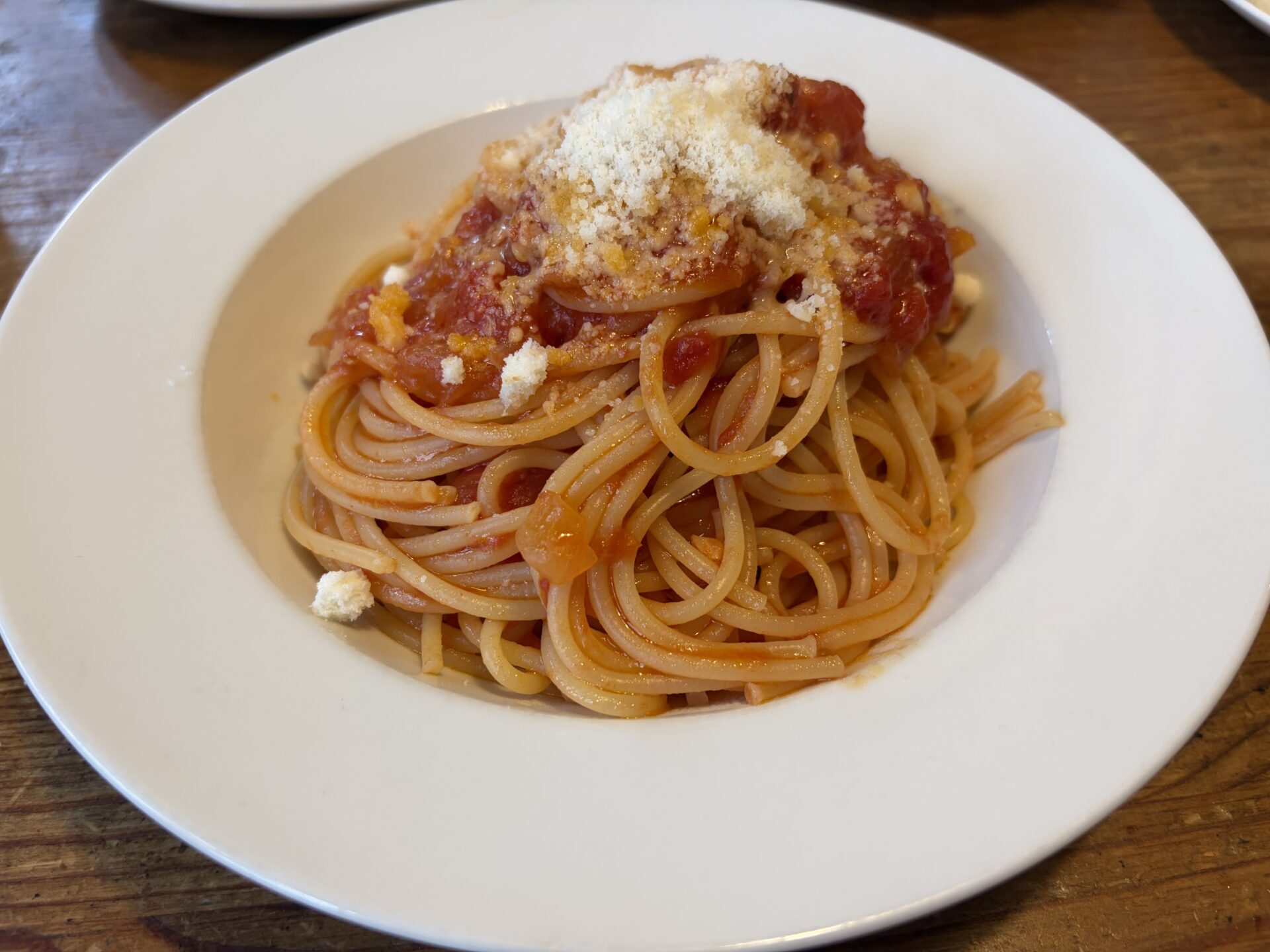 スパゲティ・ポモドーロ。トマトソースに粉チーズがかかる