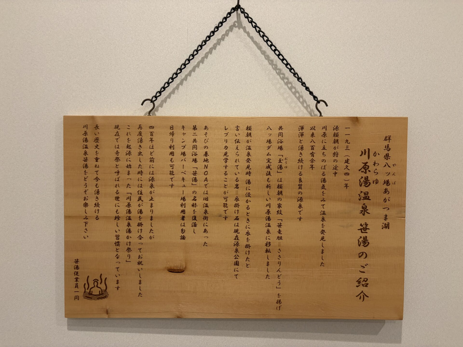 館内の木板「川原湯温泉 笹湯のご紹介」。頼朝の発見伝承から名称復活の経緯までが彫られている